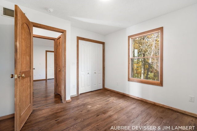 unfurnished bedroom with a closet and dark hardwood / wood-style flooring