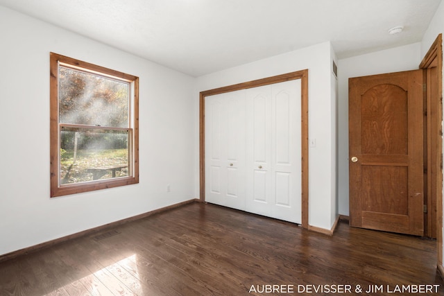 unfurnished bedroom featuring a closet and dark hardwood / wood-style flooring