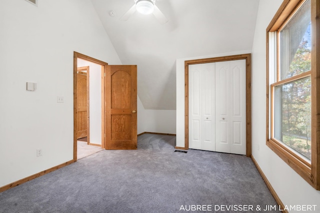 unfurnished bedroom with a closet, ceiling fan, dark carpet, and vaulted ceiling