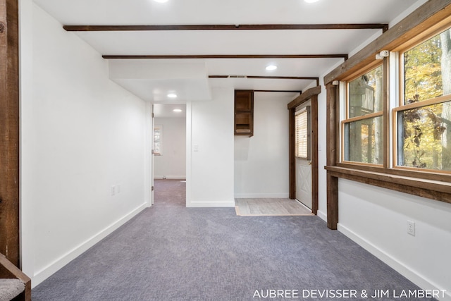 spare room featuring beamed ceiling and carpet flooring