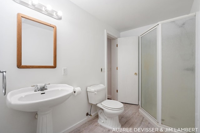 bathroom featuring a shower with door, toilet, and hardwood / wood-style flooring