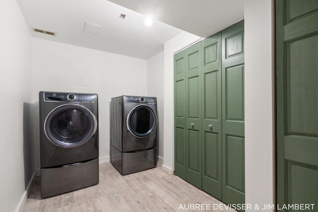 laundry room with light hardwood / wood-style floors and washer and clothes dryer