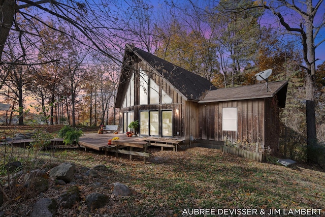 back house at dusk with a wooden deck