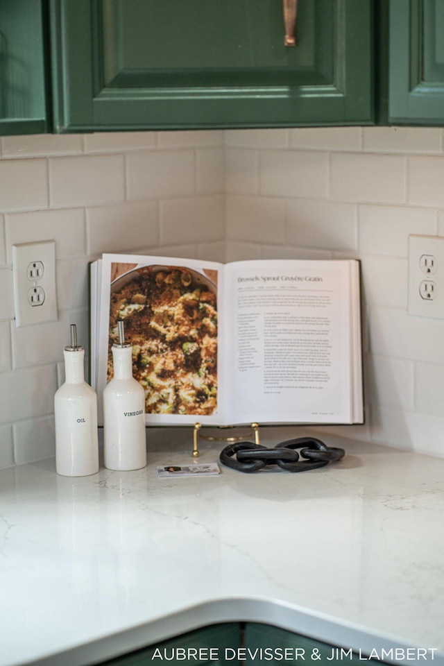 room details with light stone countertops, green cabinetry, and backsplash