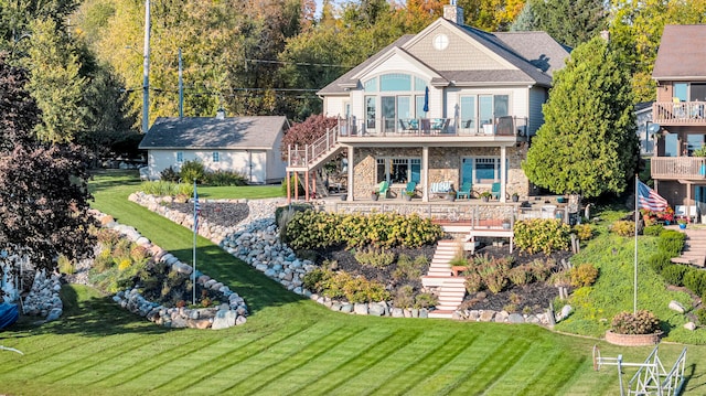 back of property with a balcony, stone siding, a chimney, stairs, and a deck