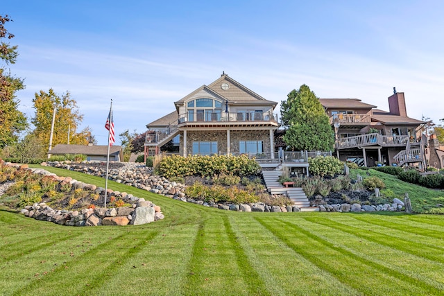 rear view of house with stone siding, stairway, a wooden deck, and a lawn