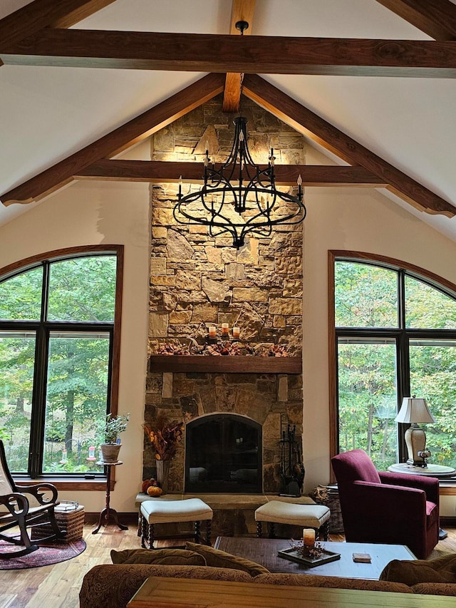 living room with a fireplace, vaulted ceiling with beams, hardwood / wood-style floors, and an inviting chandelier