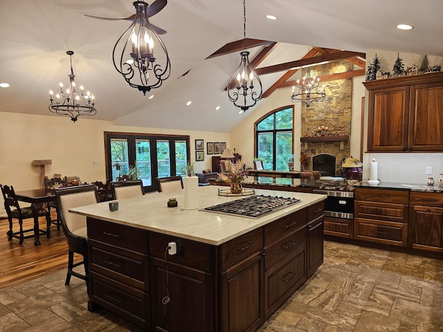 kitchen featuring a wealth of natural light, stainless steel gas cooktop, decorative light fixtures, and a breakfast bar