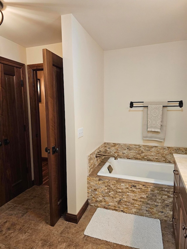 bathroom featuring a relaxing tiled tub and vanity