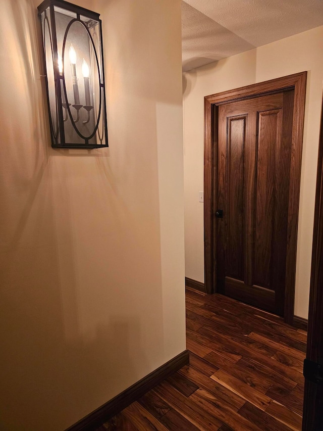 hallway with dark hardwood / wood-style floors and a textured ceiling