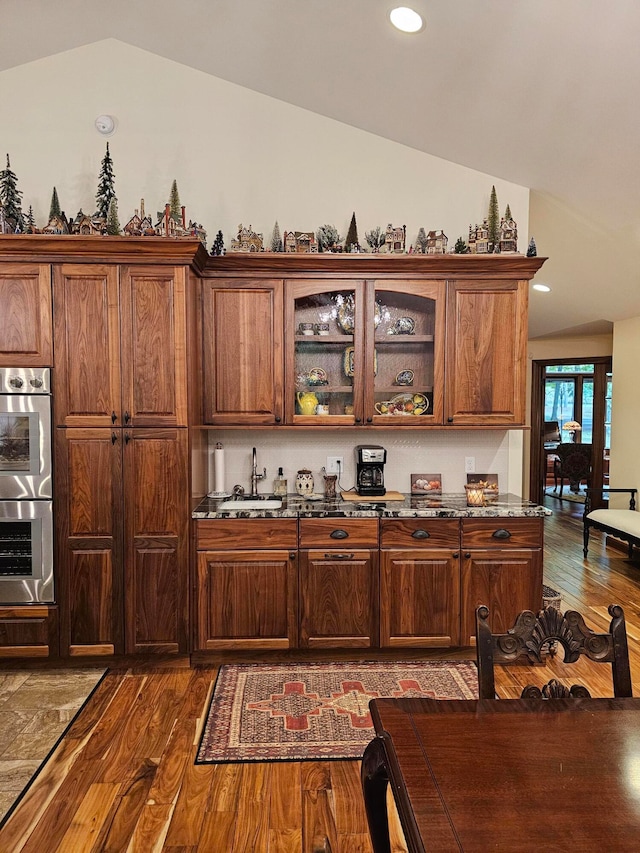 kitchen featuring sink, stainless steel double oven, vaulted ceiling, and dark hardwood / wood-style flooring