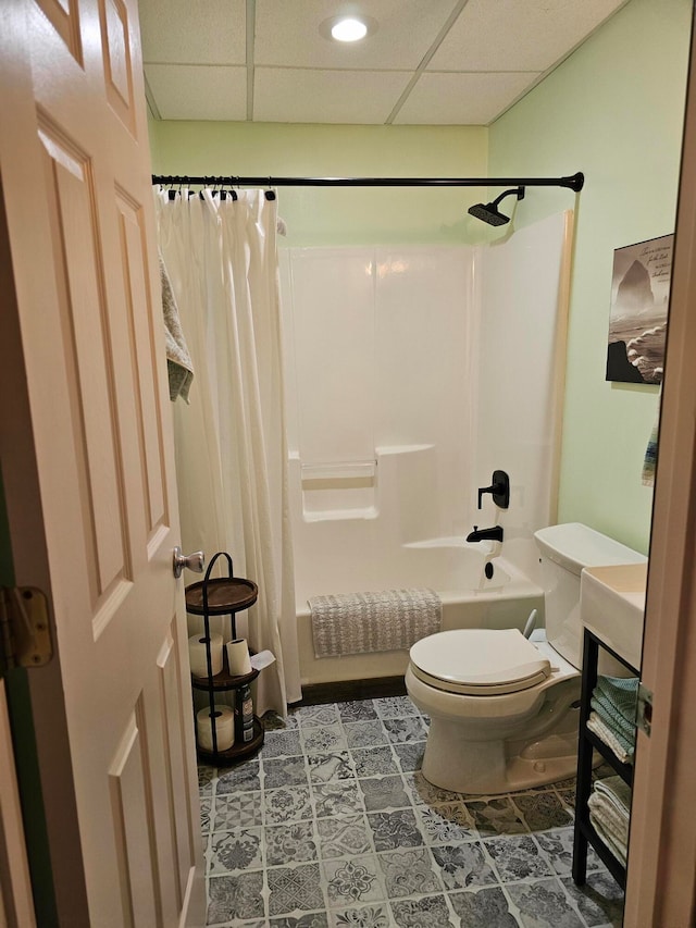 bathroom with a paneled ceiling, toilet, shower / bathtub combination with curtain, and tile patterned flooring