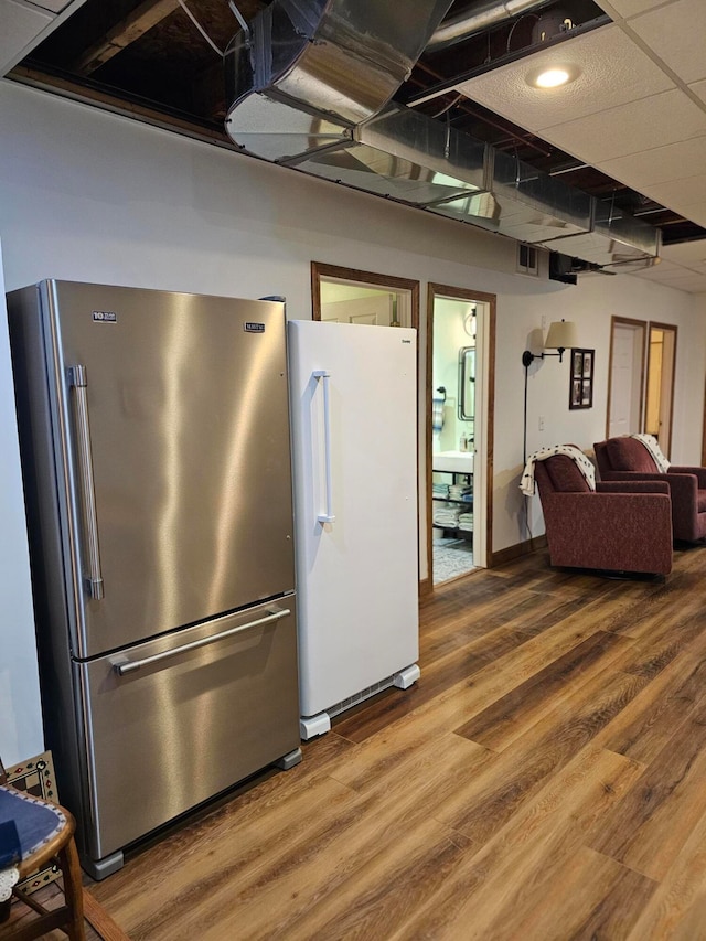 kitchen featuring wood-type flooring, white refrigerator, and stainless steel refrigerator