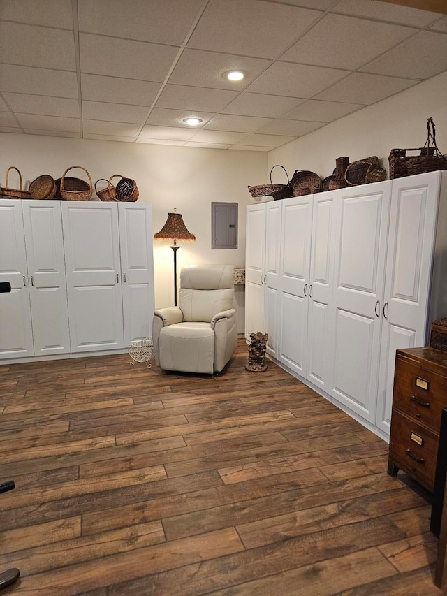 unfurnished room with a drop ceiling, electric panel, and dark wood-type flooring