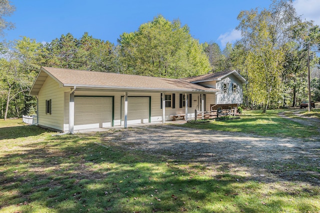 tri-level home featuring a front lawn, a porch, and a garage