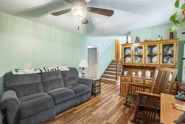 living room featuring wood-type flooring, a textured ceiling, and ceiling fan