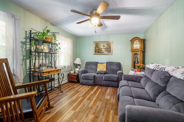 living room featuring ceiling fan, wood-type flooring, and a textured ceiling