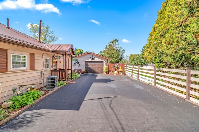 exterior space featuring a garage, cooling unit, and an outdoor structure