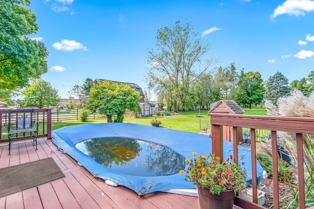 wooden terrace with a storage unit and a lawn