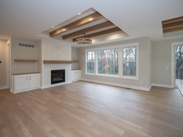 unfurnished living room featuring beam ceiling, a chandelier, a large fireplace, and light hardwood / wood-style floors