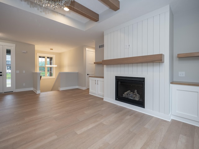 unfurnished living room featuring beam ceiling, light hardwood / wood-style floors, and a fireplace