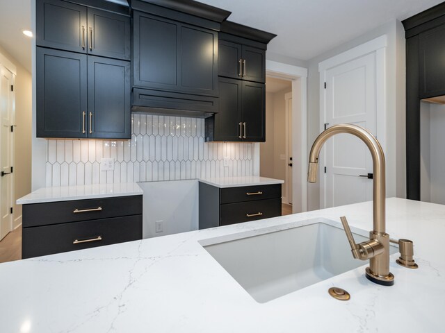 kitchen featuring decorative backsplash, light stone countertops, and sink