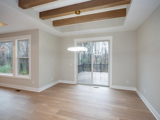 spare room with beam ceiling, light wood-type flooring, and a notable chandelier