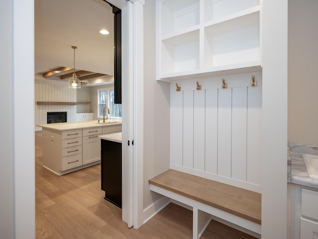 mudroom featuring a tile fireplace, light hardwood / wood-style floors, beamed ceiling, and sink