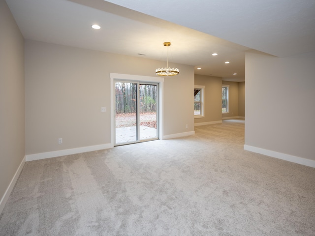 unfurnished room featuring a chandelier and light colored carpet