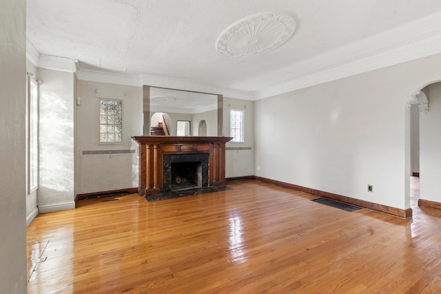 unfurnished living room with ornamental molding, a textured ceiling, a premium fireplace, and light hardwood / wood-style flooring