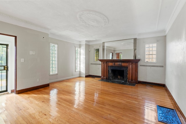 unfurnished living room with crown molding, a wealth of natural light, and light hardwood / wood-style flooring