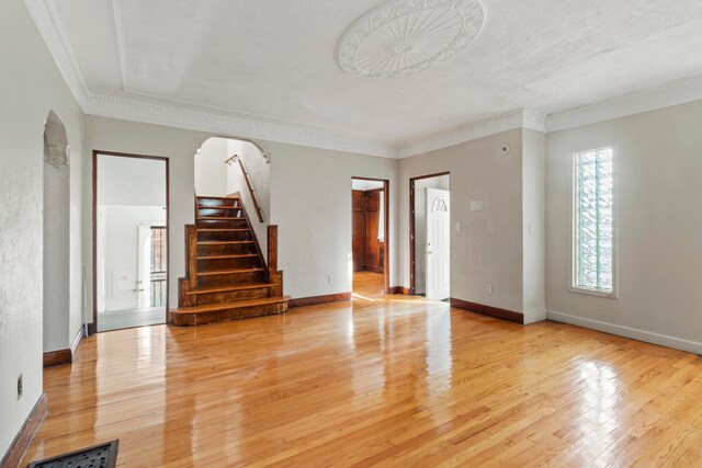 empty room featuring a textured ceiling, crown molding, and light hardwood / wood-style flooring