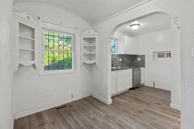 kitchen with light wood-type flooring, white cabinets, sink, and stainless steel dishwasher