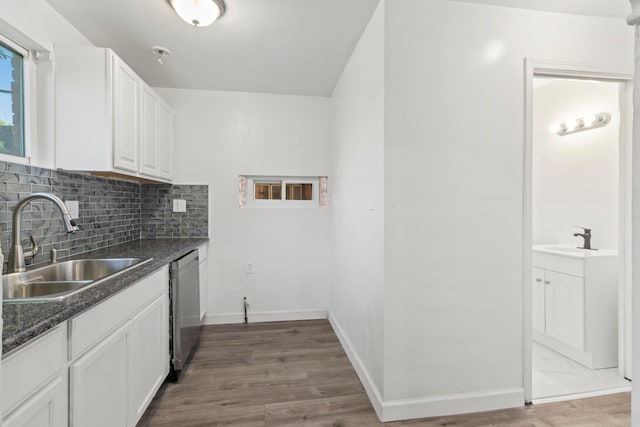 kitchen with sink, stainless steel dishwasher, wood-type flooring, white cabinetry, and dark stone countertops