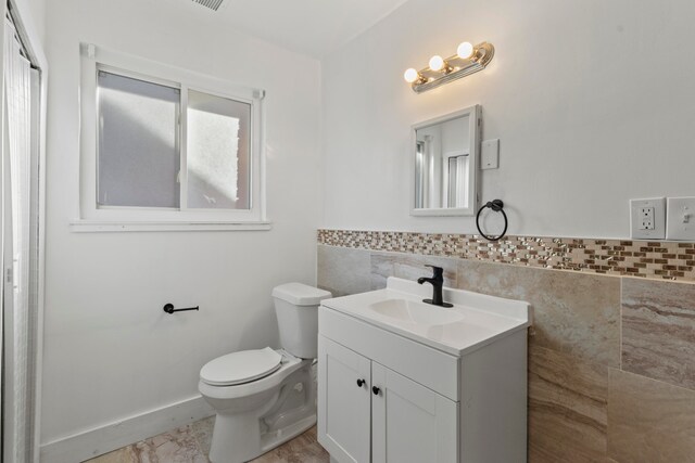 bathroom featuring vanity, tile walls, plenty of natural light, and toilet