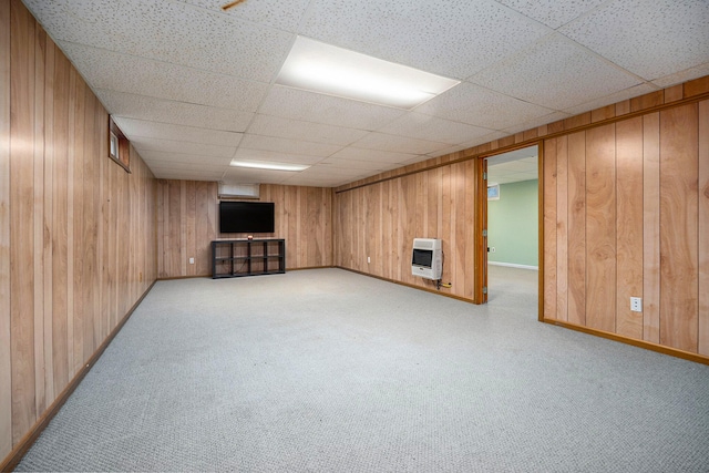 basement featuring heating unit, wooden walls, and a drop ceiling