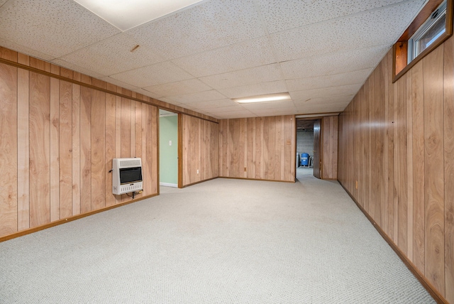 basement with heating unit, wood walls, a paneled ceiling, and light colored carpet