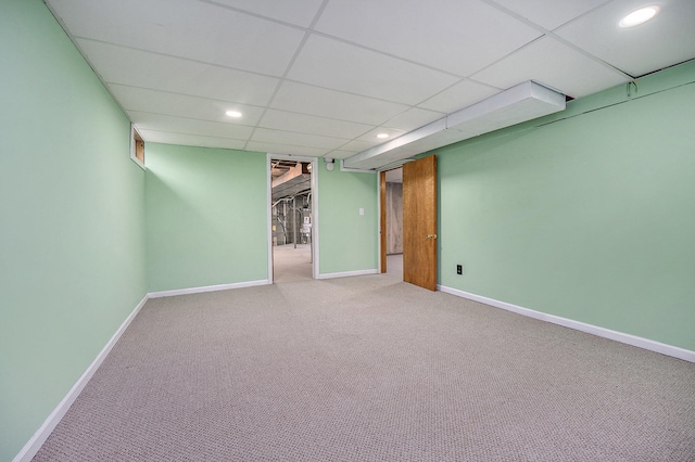 basement with a paneled ceiling and carpet