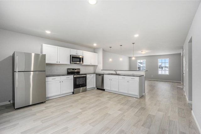 kitchen with sink, decorative light fixtures, appliances with stainless steel finishes, kitchen peninsula, and decorative backsplash