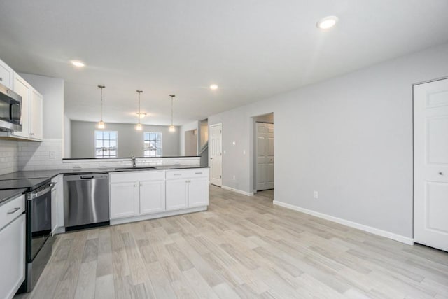 kitchen with sink, pendant lighting, stainless steel appliances, light hardwood / wood-style floors, and white cabinets