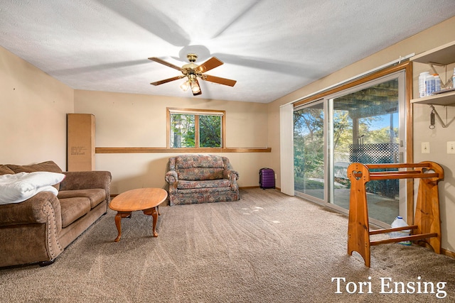 living room featuring ceiling fan, carpet floors, and a textured ceiling