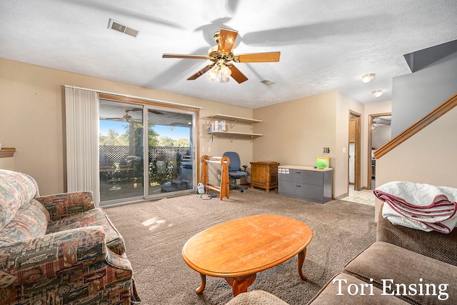 carpeted living room with ceiling fan and a textured ceiling