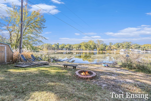 view of yard with a water view, a shed, and a fire pit