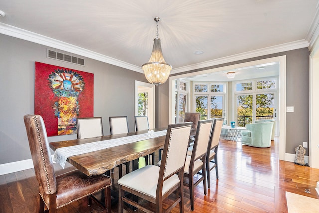 dining area with hardwood / wood-style floors, an inviting chandelier, and ornamental molding