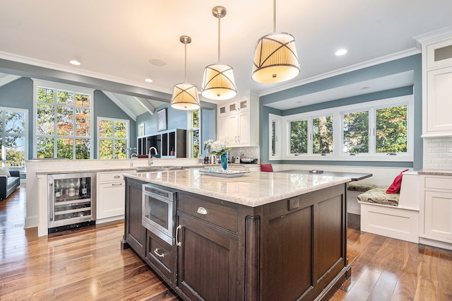 kitchen with backsplash, decorative light fixtures, white cabinetry, and beverage cooler