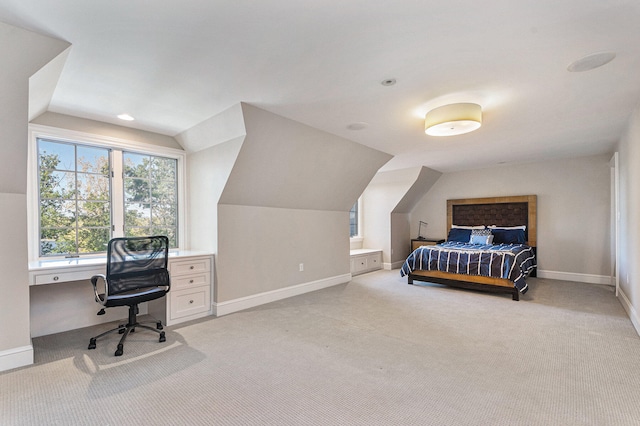 carpeted bedroom with built in desk and vaulted ceiling