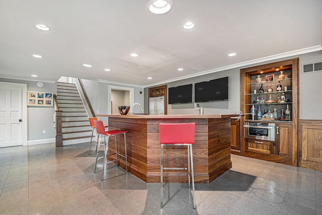 bar featuring sink, crown molding, and appliances with stainless steel finishes