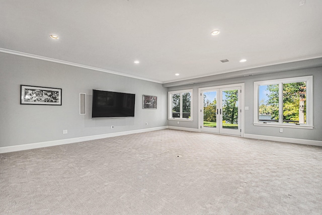 unfurnished living room with light colored carpet, crown molding, and french doors