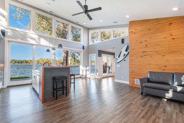 living room with a wealth of natural light, ceiling fan, and dark wood-type flooring