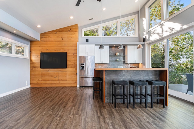 kitchen with a kitchen bar, dark wood-type flooring, built in refrigerator, white cabinetry, and hanging light fixtures